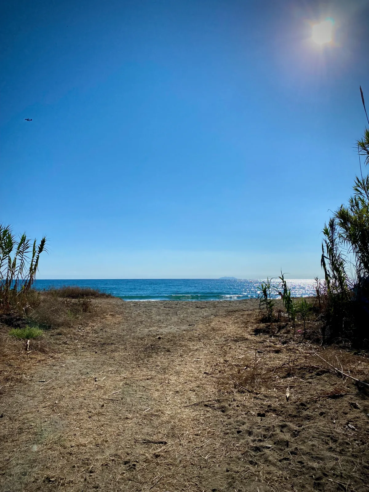 Chemin sableux vers la plage, mer au bout et grand ciel bleu