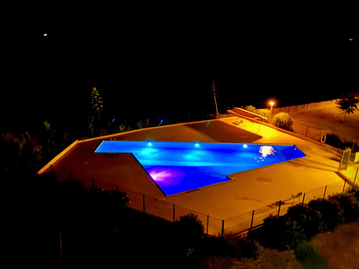 Piscine illuminée en bleu et violet la nuit à la résidence Santa Lucia