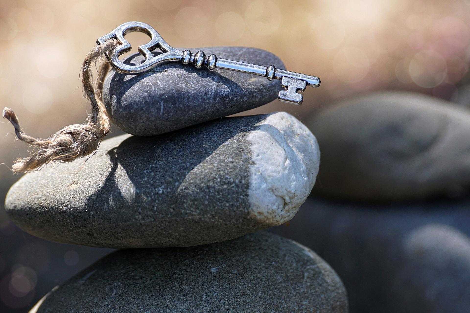 Photo of a key placed on several stacked and balanced pebbles