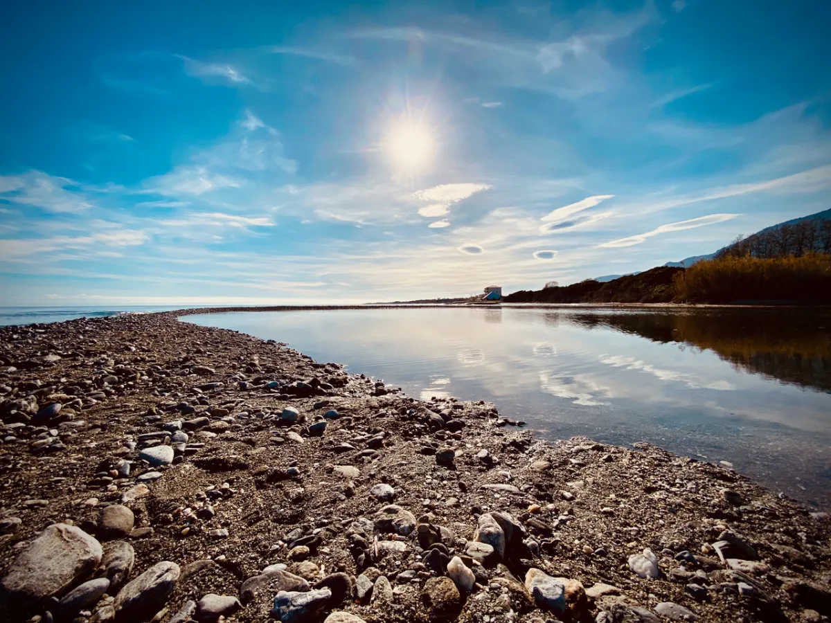 Cordon de galets entre mer et ruisseau Canapajo sous ciel bleu