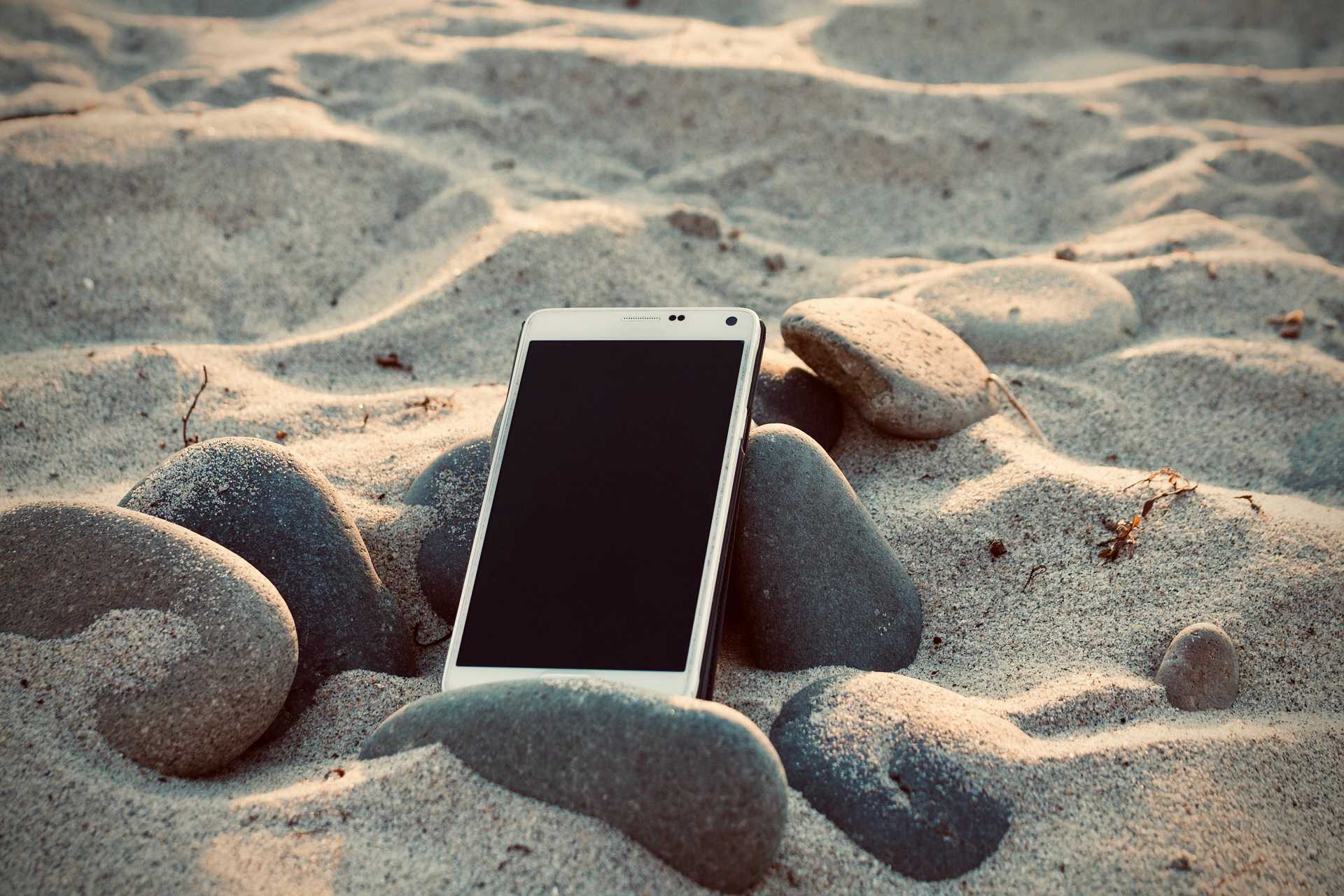 Photo d'un smartphone posé dans le sable