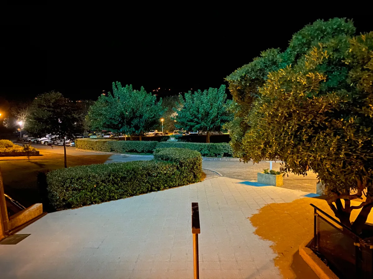 Entrée de la résidence Santa Lucia éclairée de nuit avec parking et végétation