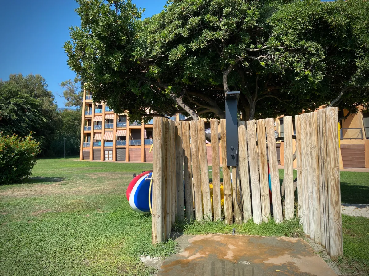 Douche extérieure en bois dans le jardin, proche de la plage