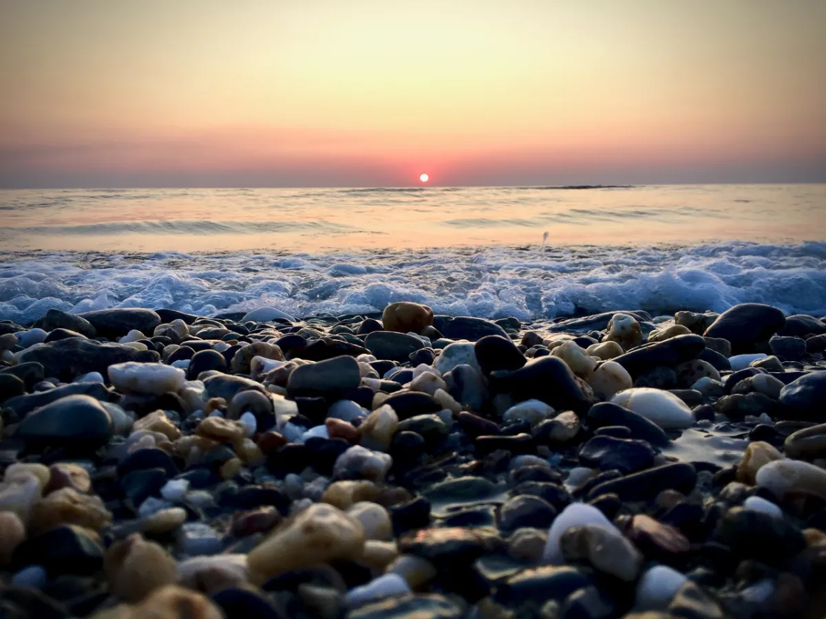 Galets en premier plan, vague et soleil couchant